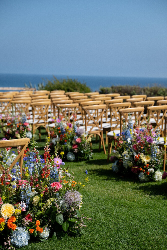 Colorful garden-style flowers lining an outdoor wedding aisle